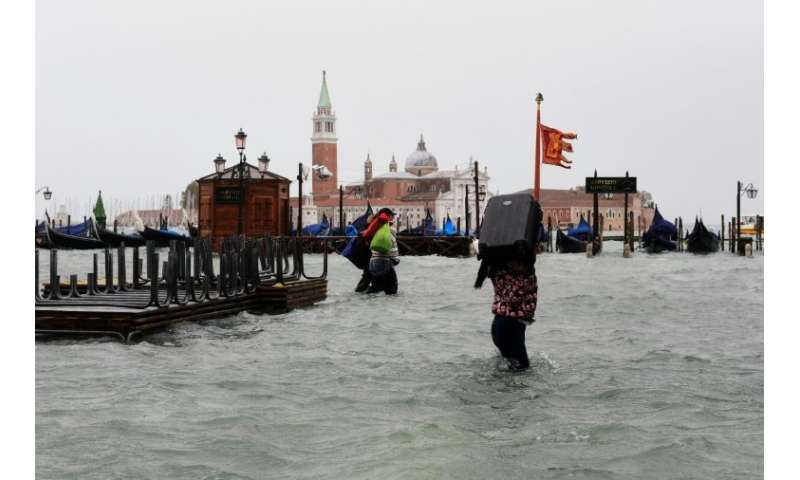 A woman carries a suitcase upon her shoulders in flooded Venice where the high water peaked at 156 centimetres (61 inches)