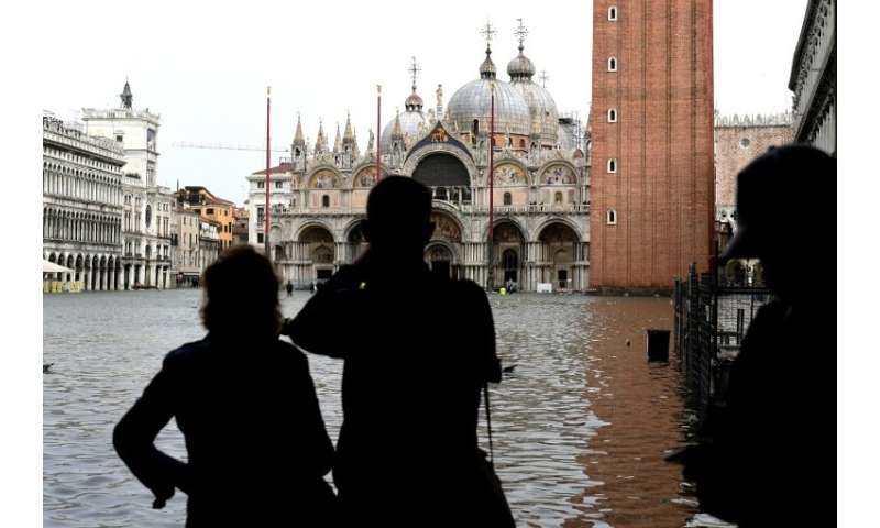 Tourists take pictures of flooded St Mark's Square where due to the  high-water (Acqua Alta) tourists were barred from walking i