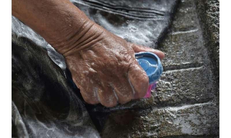 Washerwomen rub dirty clothes against rough stones at an old public laundry in Quito