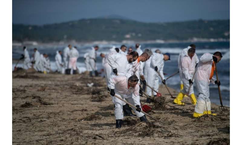Workers clean up oily residues on Pampelonne beach in the Gulf of Saint-Tropez which leaked during a collision between two ships