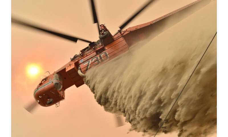 A helicopter drops fire retardent to protect a property on Australia's east coast