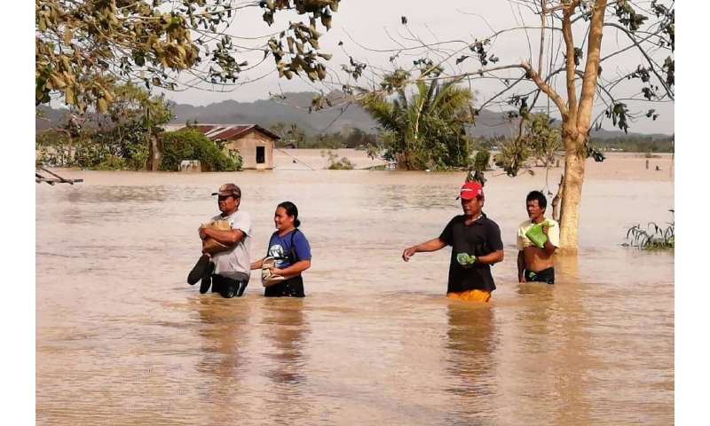 Residents wade through a highway flooded by typhoon Phanfone in Ormoc City, Leyte province