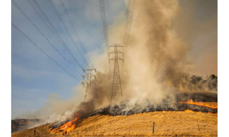 A backfire set by firefighters burns a hillside near PG&amp;E power lines during operations to battle the Kincade Fire in Healds