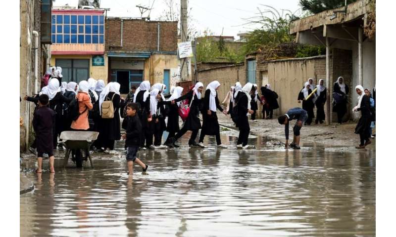 Afghan schoolgirls walk home as heavy rain falls in Kabul