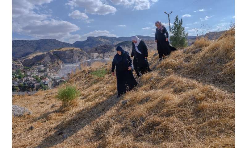 Hacire Yalcin (C) walks with her sister and her sister-in-law (R) in the  old cemetery as they search for one of their relatives