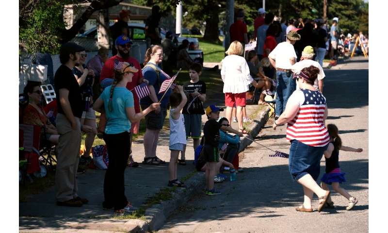 People in short-sleeve shirts seek shade as they watch a July 4, 2019 parade in Anchorage, Alaska during a record heat wave