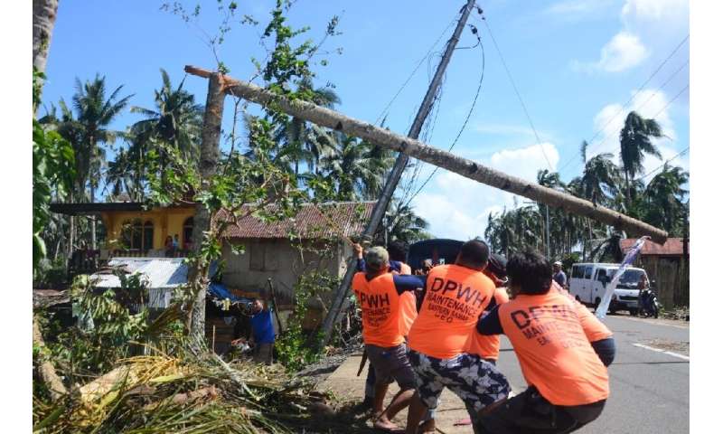 Workers pull a fallen electric pylon damaged at the height of Typhoon Phanfone in Salcedo town, Eastern Samar province of the Ph