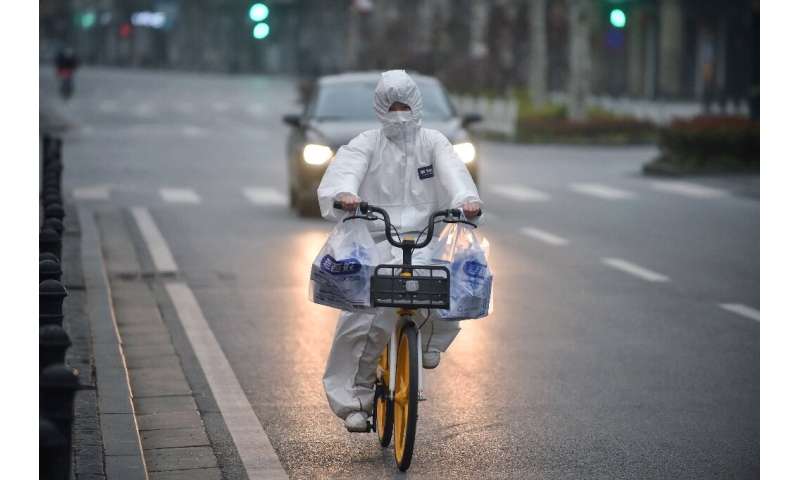 A resident wearing a protective suit rides a bicycle in the virus epicentre of Wuhan in China's central Hubei province