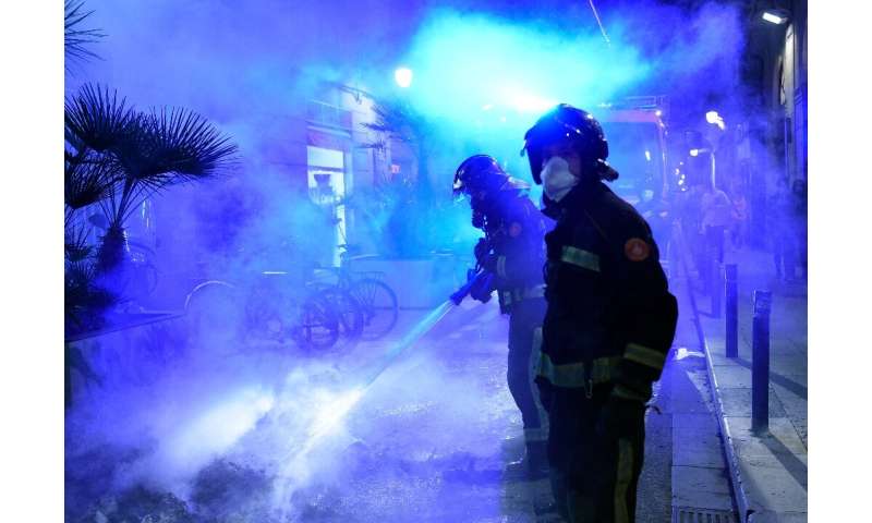 Firefighters put out a fire after a demonstration against a curfew in Barcelona as virus cases spike around Europe
