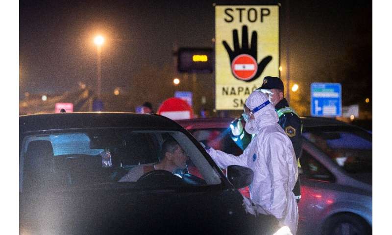 A medical worker measures body temperatures of motorists passing the Slovenian-Italian border crossing near Nova Gorica