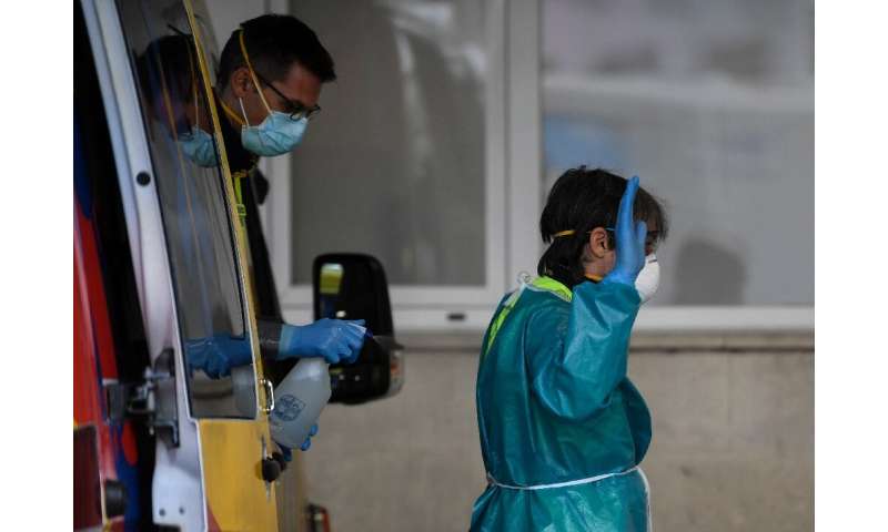 Healthcare workers disinfect their protective gear at a hospital in Madrid in Spain, one of the worst-hit countries