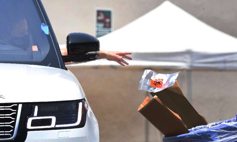 A driver drops off her coronavirus test at a COVID-19 testing site in Los Angeles, California