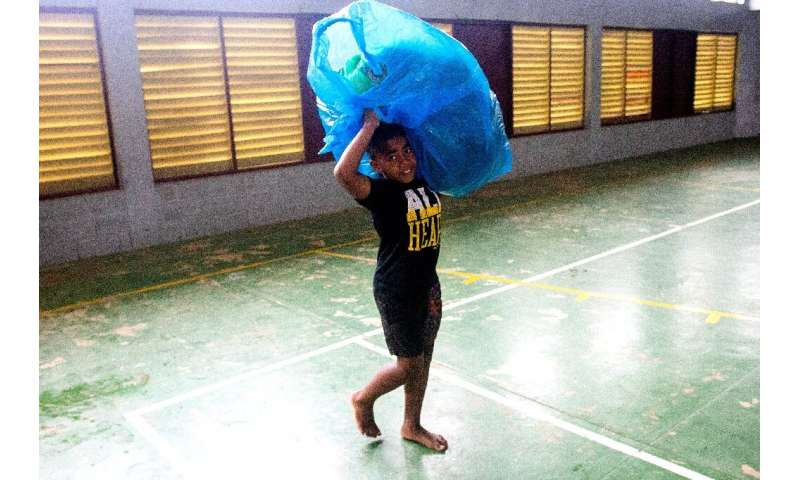 A Fijian boy carries a bag to a temporary shelter to avoid strong damaging winds from super cyclone Yasa in the capital city of 