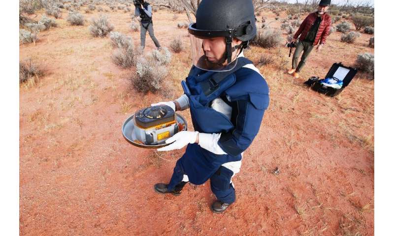 A JAXA scientist holds the capsule with samples collected from a distant asteroid that were recovered in the South Australia des