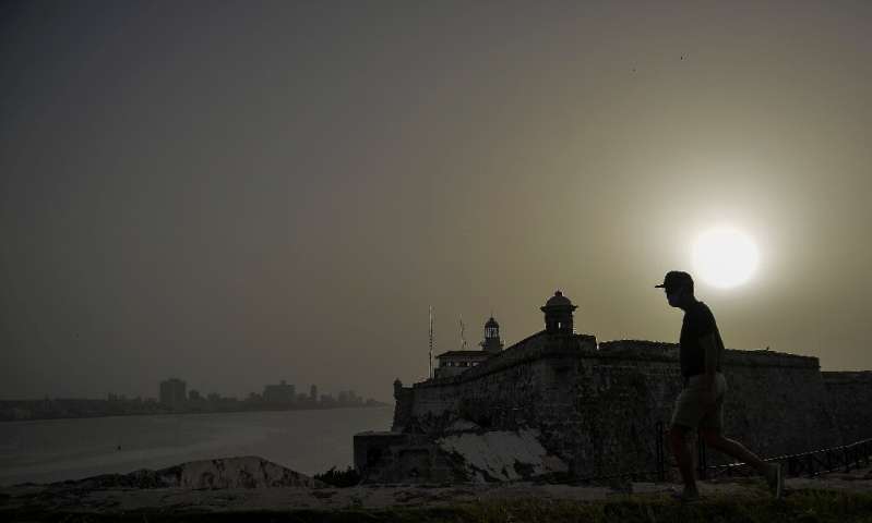 A man walks near Morro Castle as a vast cloud of Sahara dust blankets Havana