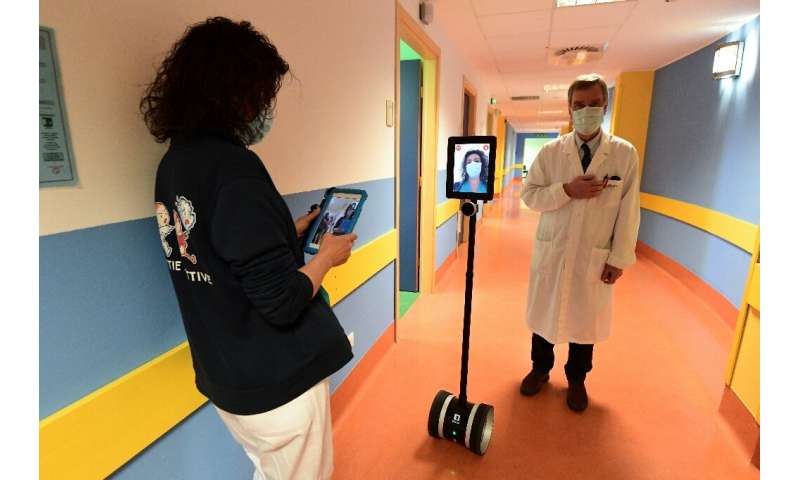 Медсестра (слева) работает с роботом, который используется для обследования тяжело больных пациентов с коронавирусом в Варезе, северная Италия.