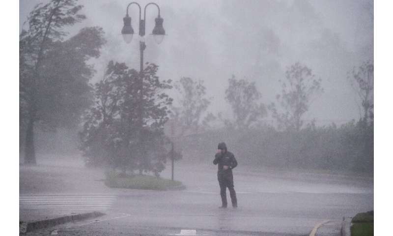 A reporter covers his face as Hurricane Delta makes landfall in Lake Charles, Louisiana on October 9, 2020