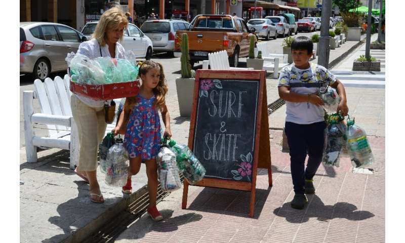 A Uruguayan woman and her grandchildren take plastic bottles to a collection center in Priapolis on January 22