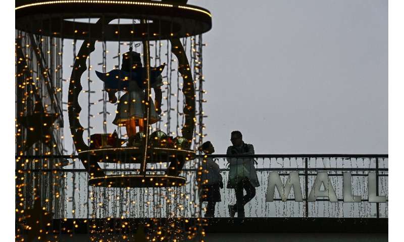 Customers stand on a balcony next to Christmas decorations in a shopping mall in Berlin. Germany plans to ease virus curbs for C