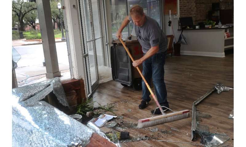 Morgan Griffin cleans up a broken window in the store where he works in Mobile, Alabama, after Hurricane Sally