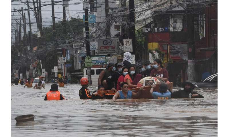Rescuers evacuate residents from their flooded homes in Manila