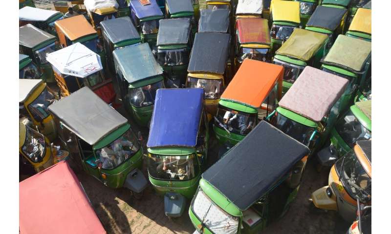 Rickshaw drivers in Rawalpindi gather at a food distribution site set up by the traffic police during a government-imposed natio
