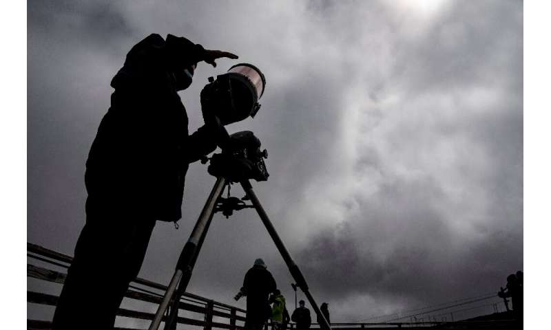 Simon Angel, an astronoma from the Catholic University of Chile, sets up his telescope to view the eclipse