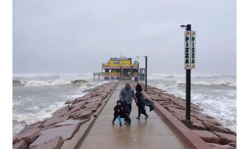 Spectators look out towards the Gulf of Mexico as the outer bands of Hurricane Delta reach Galveston, Texas on October 9, 2020