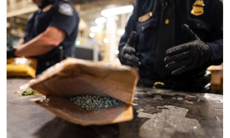 An officer from US Customs and Border Protection finds Oxycodon pills in a parcel at John F. Kennedy Airport in June 2019 in New