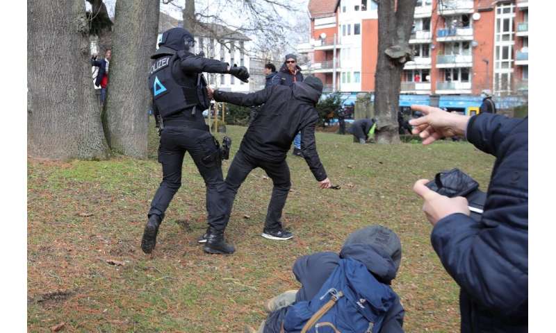 A protester and a policeman clash on the sidelines of an anti-Covid restriction demonstration in the German city of Kassel