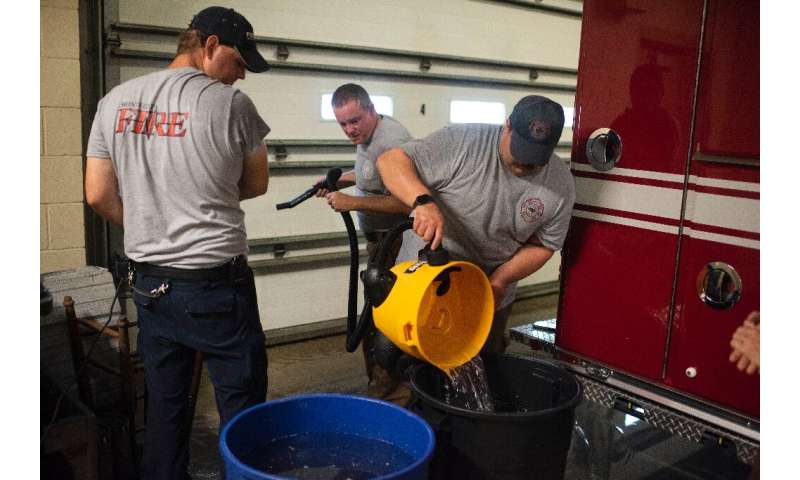 Firefighters use a wet vaccum to soak up water leaking into a firestation as Hurricane Ida passes in Bourg, Louisiana on August 