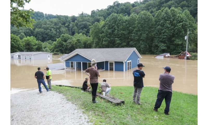 A family looks at their submerged home in Jackson, Kentucky