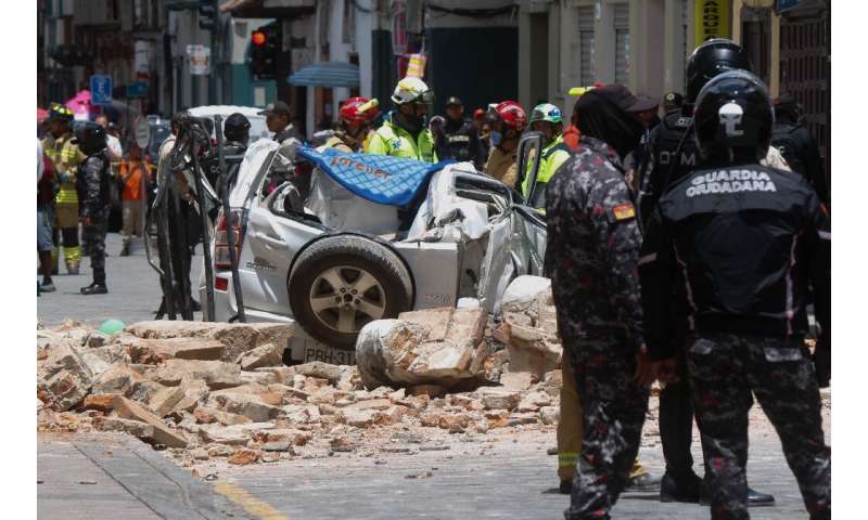 Un automóvil aplastado por una pieza de un edificio se ve en el centro histórico de la ciudad ecuatoriana de Cuenca el 18 de marzo de 2023.