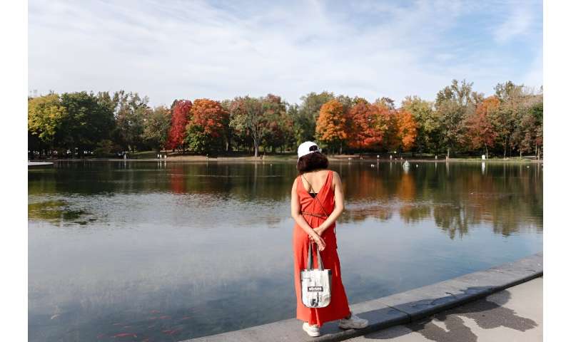 A woman stands near the Lac-aux-Castors in Montreal, taking in warm autumn weather