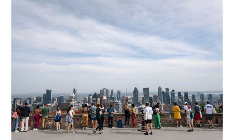 Tourists snap pictures of the city at the Mont-Royal belvedere in Montreal while soaking in unseasonably hot weather