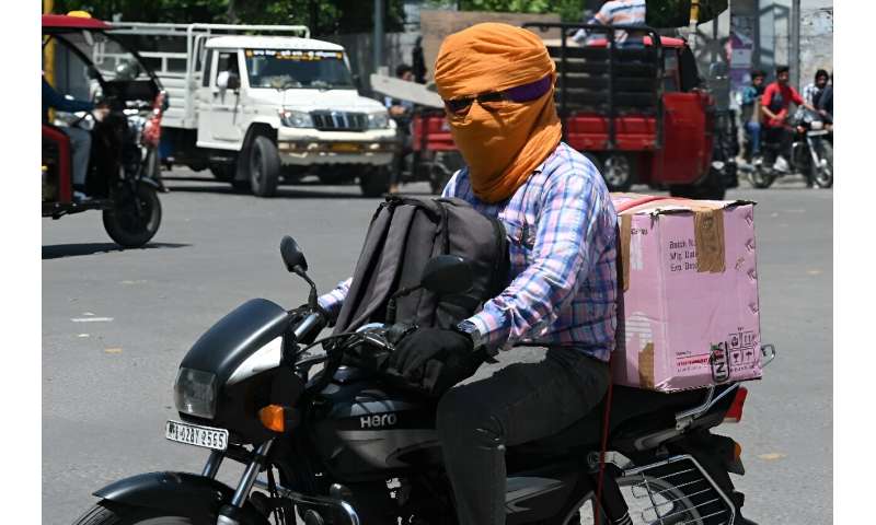 A man on a motorcycle has his face covered with a scarf to shelter from the heat in Amritsar in India