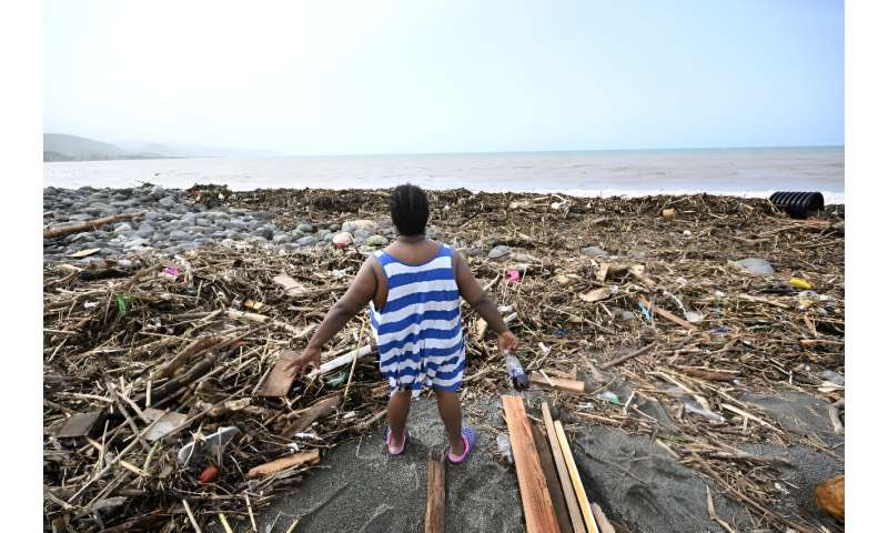 A woman looks at a Jamaican beach littered with trash in the aftermath of Hurricane Beryl