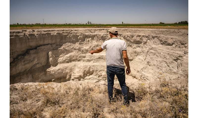 Farmer Yigit Aksel looks into a large sinkhole near his home in Karapinar in central Turkey