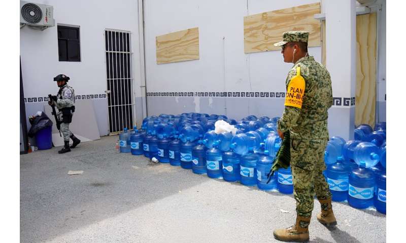 Military personnel stand close to stockpiles of water before Hurricane Beryl's arrival in Tulum