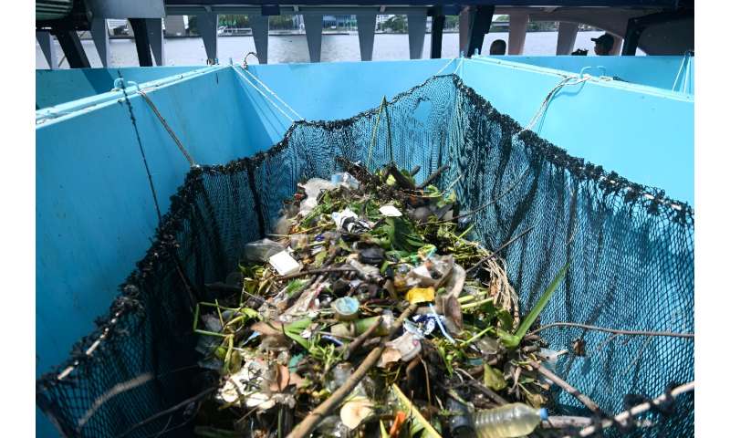 Ticking bamboo-slatted treadmills carry the collected waste into the barge, where it is deposited into bright blue skips and taken ashore to be disposed of by local authorities