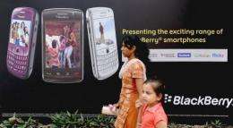 An Indian woman and child walk past a billboard for Blackberry phones in Mumbai