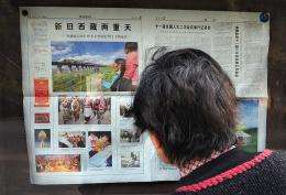 A woman reads a state media newspaper