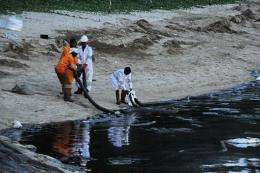 Emergency workers attempt to clear the crude oil slick