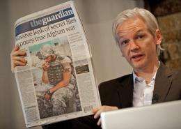 Julian Assange holds up a copy of the Guardian newspaper