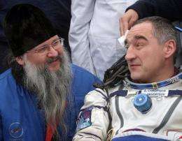Russian cosmonauts Alexander Skvortsov (R) speaks with an Orthodox priest