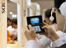 Visitors examine Nintendo's portable videogame console with a 3D display called the "Nintendo 3DS"