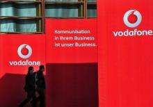 Visitors walk past Vodafone exhibition stand walls