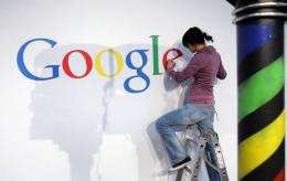 A stand builder fixes a logo at the Google stand