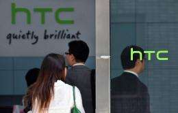 People walk past High Tech Computer Corp. (HTC) logos