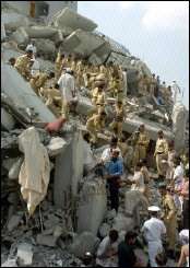 Pakistani policemen and rescuers remove debris from a collapsed building hit by a massive earthquake in Islamabad